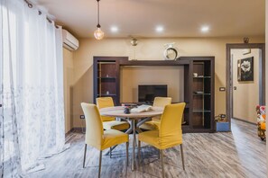 A dining area with a round table, four chairs, a fireplace, and a bookshelf.