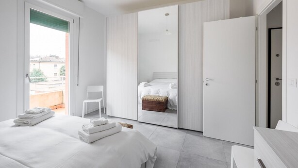 Een moderne hotelkamer met een groot bed, een zithoek en een schuifdeur naar een balkon.