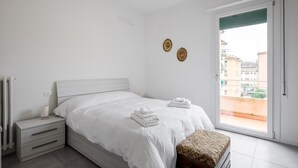 Een slaapkamer met een bed, nachtkastje en uitzicht.