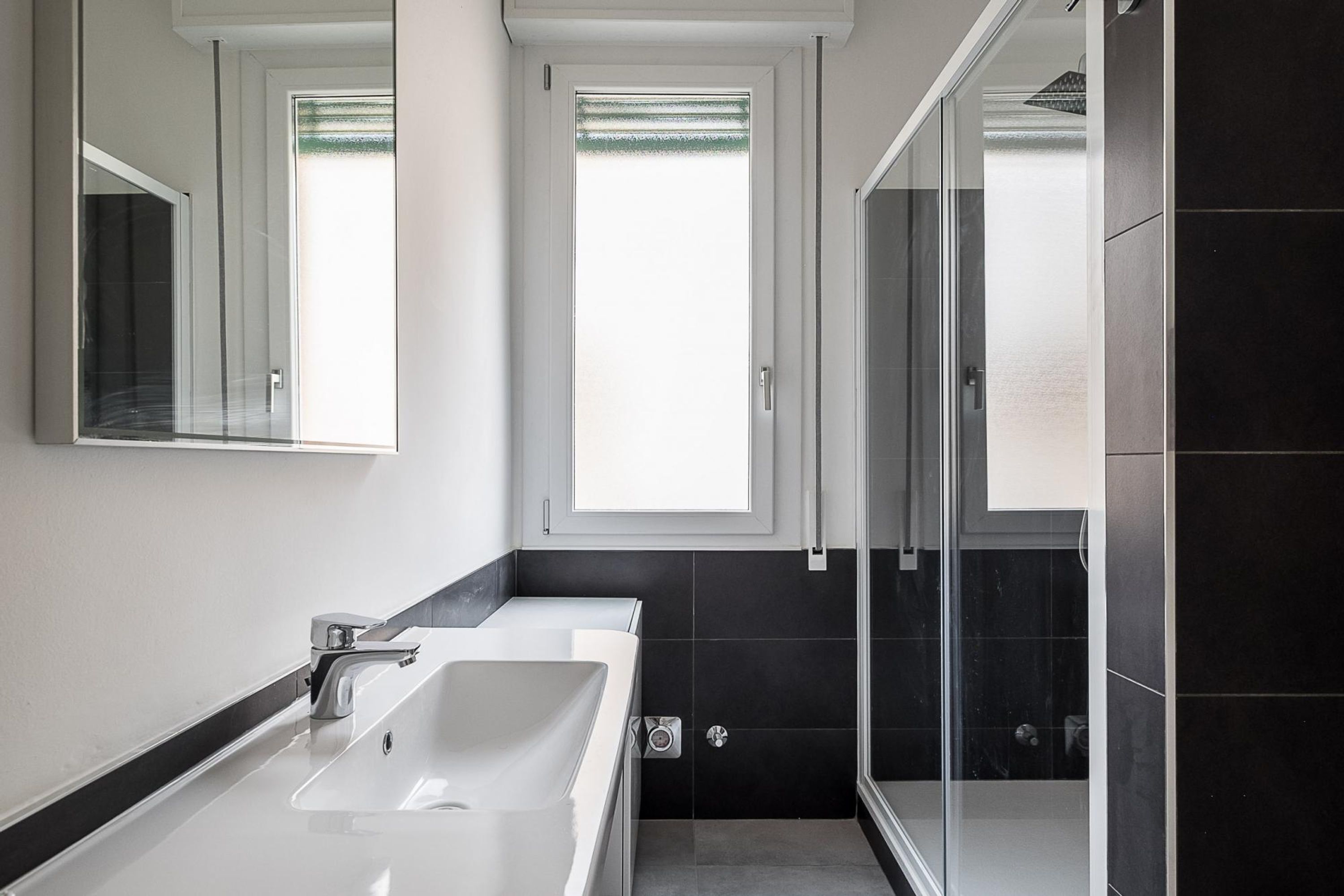 A modern bathroom with a double sink, a large mirror, and a glass shower enclosure.