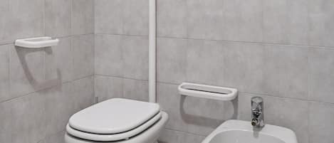 A bathroom with a toilet, bidet, and a wall-mounted tank.