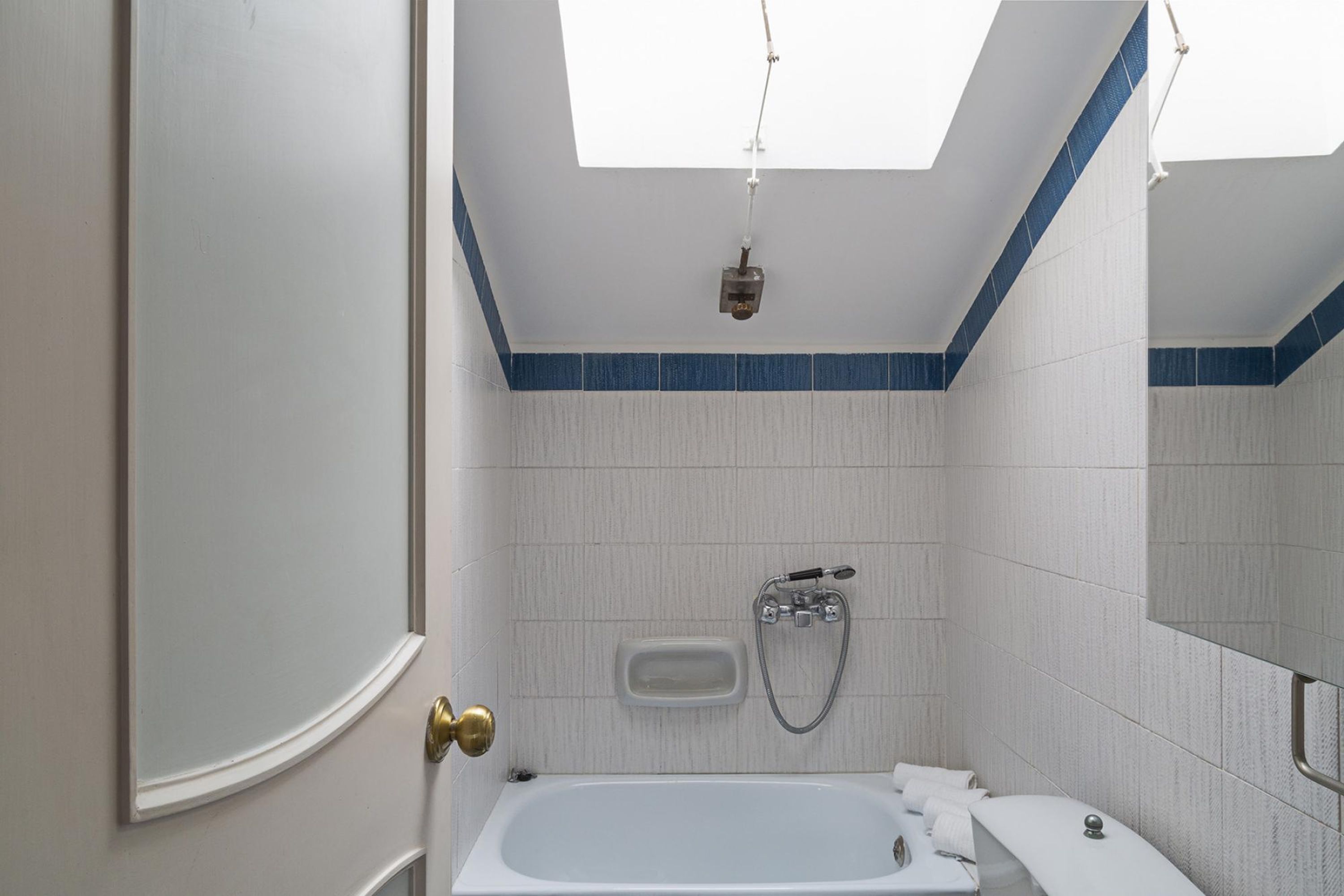 Ein Badezimmer mit Badewanne, Dusche und Toilette. Über der Badewanne befindet sich ein Oberlicht.