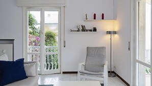 A modern living room with a sofa, a chair, a floor lamp, and a bookshelf. - Casa Bianca a Bogliasco by Wonderful Italy (Bogliasco)