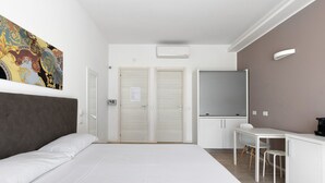 A modern hotel room with a large bed, a desk with a chair, a window with blinds, and a colorful artwork on the wall. - Cineteca Grey Studio I by Wonderful Italy (Bologna)