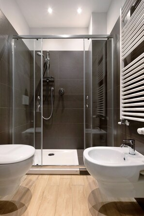 A modern bathroom with a glass-enclosed shower, two sinks, and a towel rack.