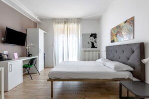 A modern hotel room with a bed, a desk with a computer, a TV, and a painting on the wall. - Cineteca Grey Studio I by Wonderful Italy (Bologna)