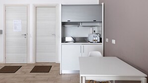 A compact kitchen with a white table, two doors, and a built-in oven.