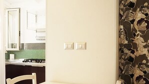 A kitchen with a stove, a chair, and a wall with two light switches. - Dependance in Villa con Piscina by Wonderful Italy (Syracuse)