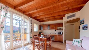 A cozy kitchen with wooden cabinets, a dining table with chairs, and a large window with curtains. - Borgo del Torchio A14 con Piscina by Wonderful Italy (Manerba del Garda)