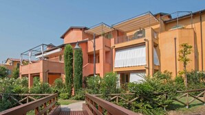 A row of terraced houses with balconies, a wooden bridge, and a garden area. - Borgo del Torchio A14 con Piscina by Wonderful Italy (Manerba del Garda)