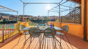 A terrace with a table set for two, surrounded by metal chairs, overlooking a pool and residential buildings. - Borgo del Torchio A14 con Piscina by Wonderful Italy (Manerba del Garda)