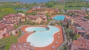 Un complexe hôtelier doté d’une grande piscine, de plusieurs bâtiments aux toits recouverts de tuiles rouges et offrant une vue sur la mer.