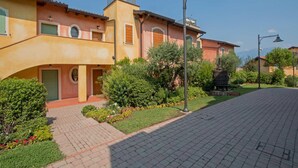 A residential building with a brick pathway, green door, and a small garden area. - Borgo del Torchio A14 con Piscina by Wonderful Italy (Manerba del Garda)