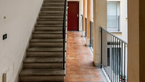 Ein Korridor mit Holzboden, einer Treppe und einer roten Tür am Ende.