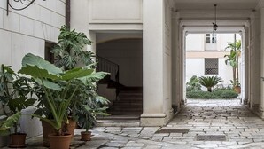 Un patio con piso de piedra, plantas en macetas y una escalera que lleva a un nivel superior.