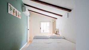 Un dormitorio con cama, ventana y aire acondicionado instalado en la pared.