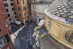 An aerial view of a historic square with buildings featuring classical architecture, a cobblestone street, and outdoor seating areas.