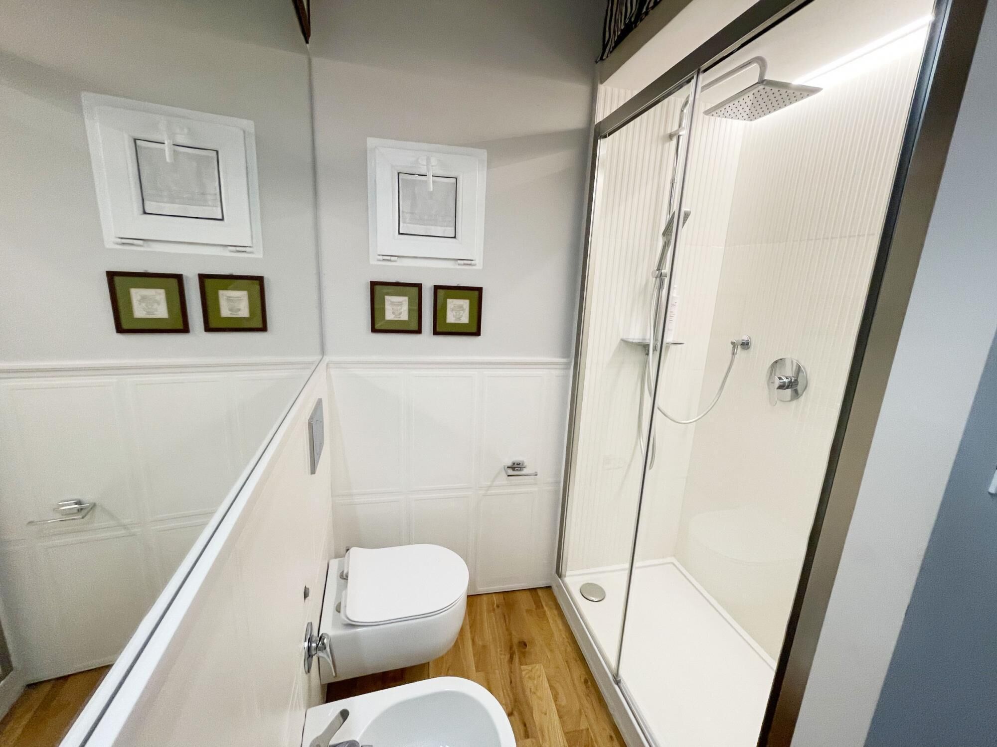 Une salle de bain moderne équipée de toilettes, d’un bidet et d’une douche à parois de verre.