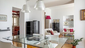 Ein modernes Wohnzimmer mit einem Glastisch, weißen Sofas und einer roten Lampe.