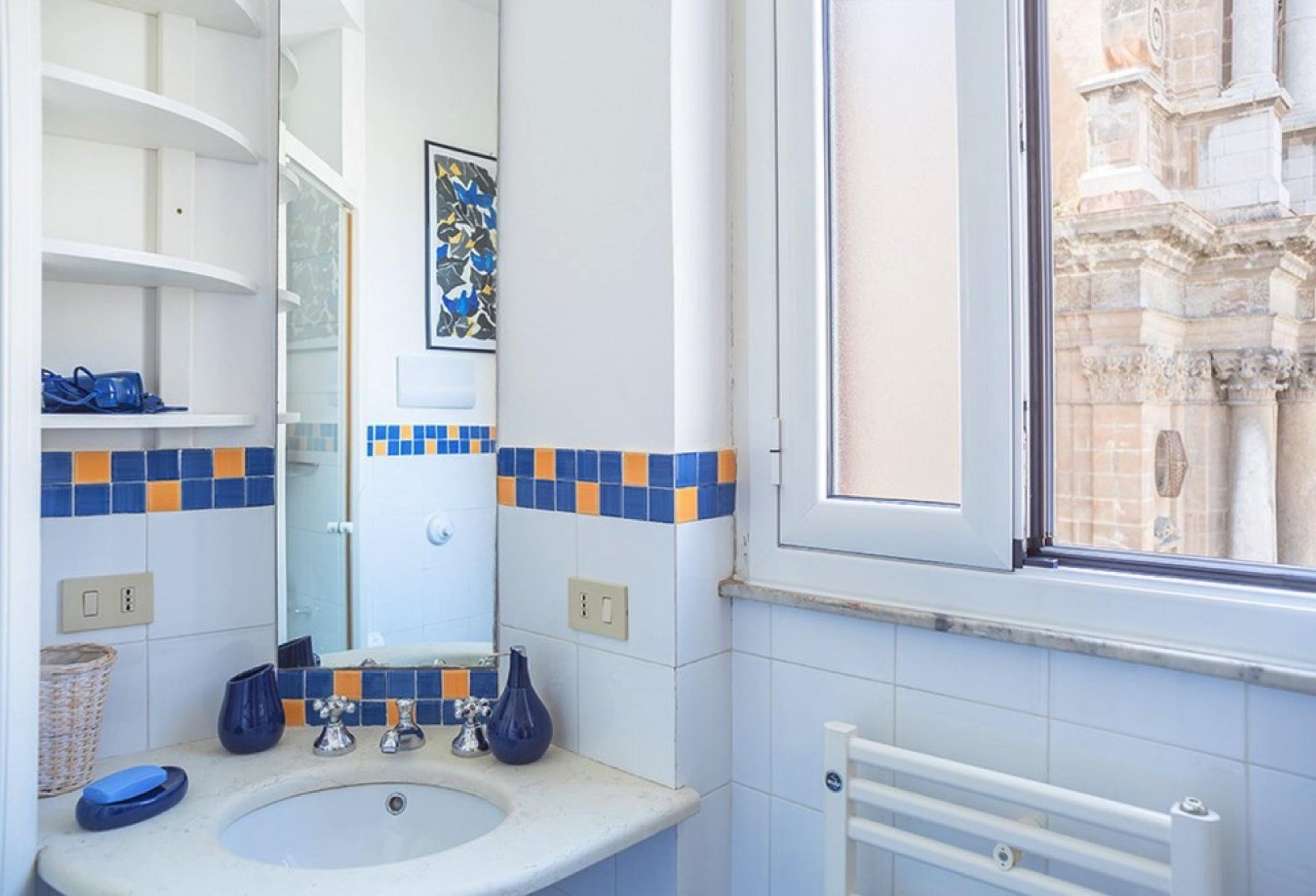 Une salle de bain avec un lavabo, un miroir et des étagères.