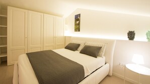 A bedroom with a bed, a bedside table, a lamp, and a wardrobe.