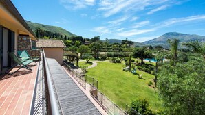 A balcony with a view of a lush garden, a pool, and distant hills. - L Ulivo Blu - One-bedroom With Balcony by Wonderful Italy (Castellammare del Golfo)