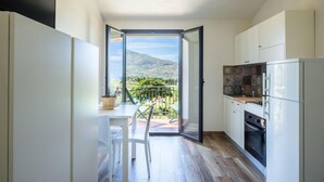 A compact kitchen with a sliding glass door leading to a balcony with a mountain view. - L Ulivo Blu - One-bedroom With Balcony by Wonderful Italy (Castellammare del Golfo)