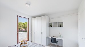 A modern bedroom with a bed, a desk, and a chair. There is a window with a view of greenery outside. - I Ciliegi 1-09 con Piscina by Wonderful Italy (Desenzano del Garda)