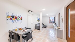 A modern kitchen with a dining area, a gray sofa, and a tiled floor. - I Ciliegi 1-09 con Piscina by Wonderful Italy (Desenzano del Garda)