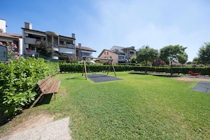 Enjoy a family-friendly atmosphere in this well-maintained outdoor space with a lawn, bench, and swing set.