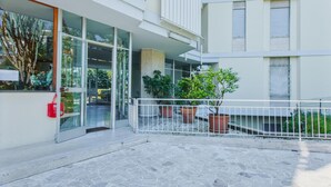 Een modern gebouw met grote glasramen, een straat van stenen tegels en potplanten.