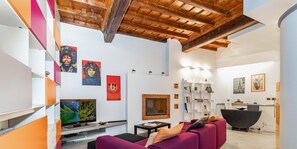 Una sala de estar moderna con techo de madera, un televisor, una chimenea y un sofá rojo.