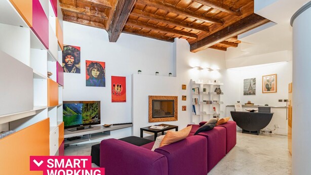 A modern living room with a purple sofa, a flat-screen TV, and artwork on the walls.