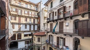 A narrow street with multi-story buildings, balconies, and a small courtyard.