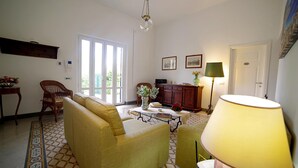 A living room with a sofa, a coffee table, a lamp, and a bookshelf. - Villa Flores a Mondello by Wonderful Italy (Palermo)