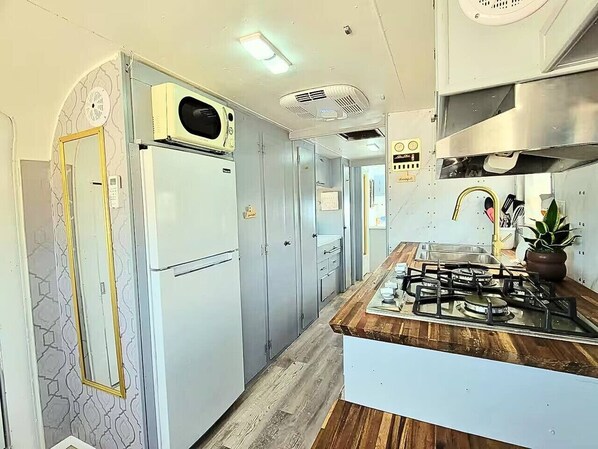 Una cocina compacta con estufa a gas integrada, un refrigerador y un microondas.