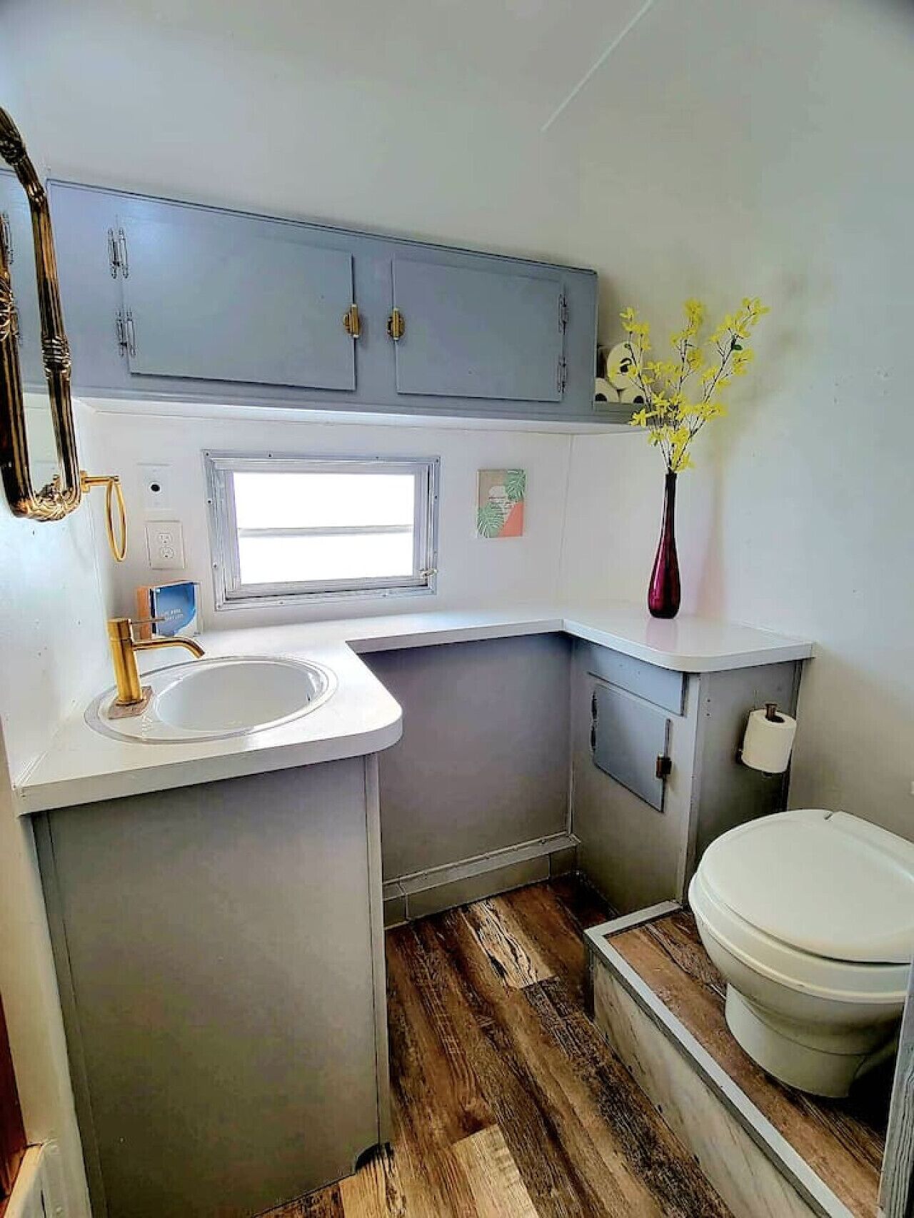 A compact kitchenette with a sink, a window, and a toilet.