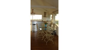 A dining area with a glass table and wicker chairs, a bar stool, and a vase with flowers. - Villa Lara is a 2-minute walk from the beach! Heated pool and 180° ocean view (Sibiril)