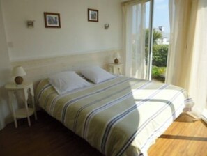 A bedroom with a bed, two bedside tables, and a window with curtains. - Villa Lara is a 2-minute walk from the beach! Heated pool and 180° ocean view (Sibiril)