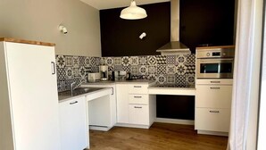 A compact kitchen with white cabinets, a built-in oven, and a coffee maker. - Gites-domainedupin, cottage "Mosnes à Lisa" (Mosnes)