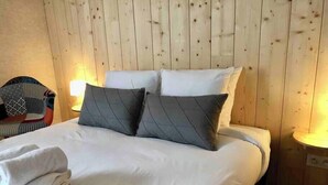 A neatly made bed with white linens and two gray pillows, a folded towel, and a wooden headboard. - Gites-domainedupin, cottage "Mosnes à Lisa" (Mosnes)