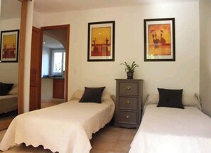 Een hotelkamer met twee enkele bedden, een dressoir en kunst aan de muren.