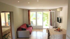 Un soggiorno con un divano, un tavolo da pranzo con tovaglia fantasia e una TV montata a parete.