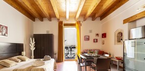 A hotel room with a bed, a desk, a dining area, and a kitchen.
