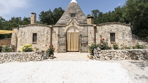 A stone building with a conical roof, a central door, and small windows. - Trullo Fragno by Wonderful Italy (Noci)