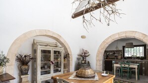 A rustic kitchen with stone arches, a wooden dining table, and a hanging light fixture. - Trullo Fragno by Wonderful Italy (Noci)