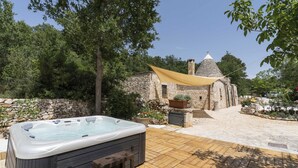 A hot tub on a wooden deck with stone walls and a stone building in the background. - Trullo Fragno by Wonderful Italy (Noci)