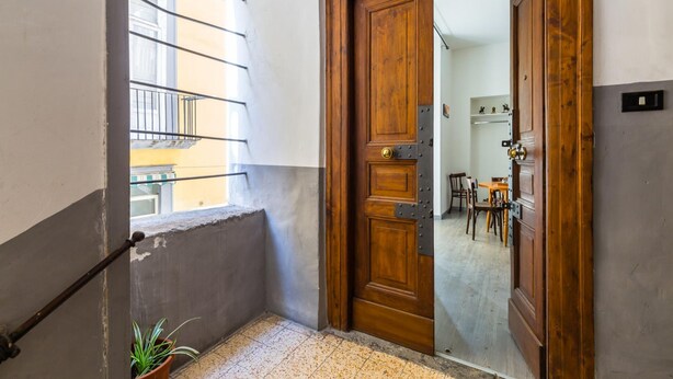 Une porte en bois qui donne sur une pièce où se trouvent une table à manger et des chaises.