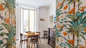 Un coin repas avec une table et des chaises en bois, une vue sur l’extérieur et une bibliothèque remplie de livres.