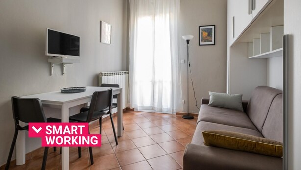 Uma sala de estar moderna com área de jantar, sofá, televisão e luminária.